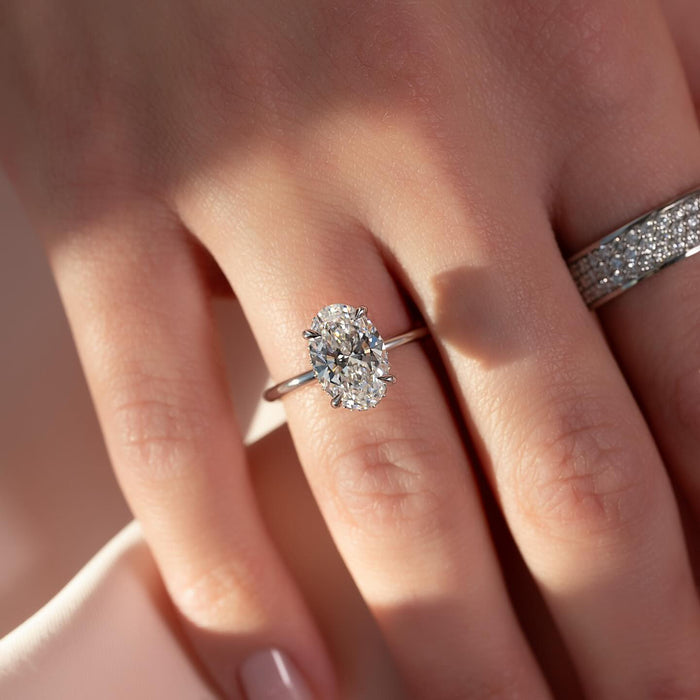 Oval moissanite hidden halo solitaire ring worn on hand in white gold