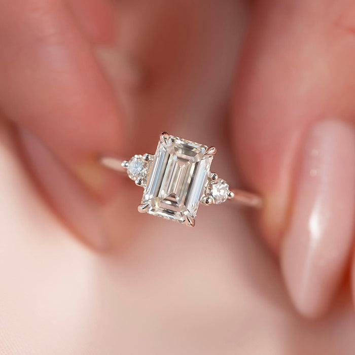 Emerald cut moissanite ring close up with round side stones in white gold