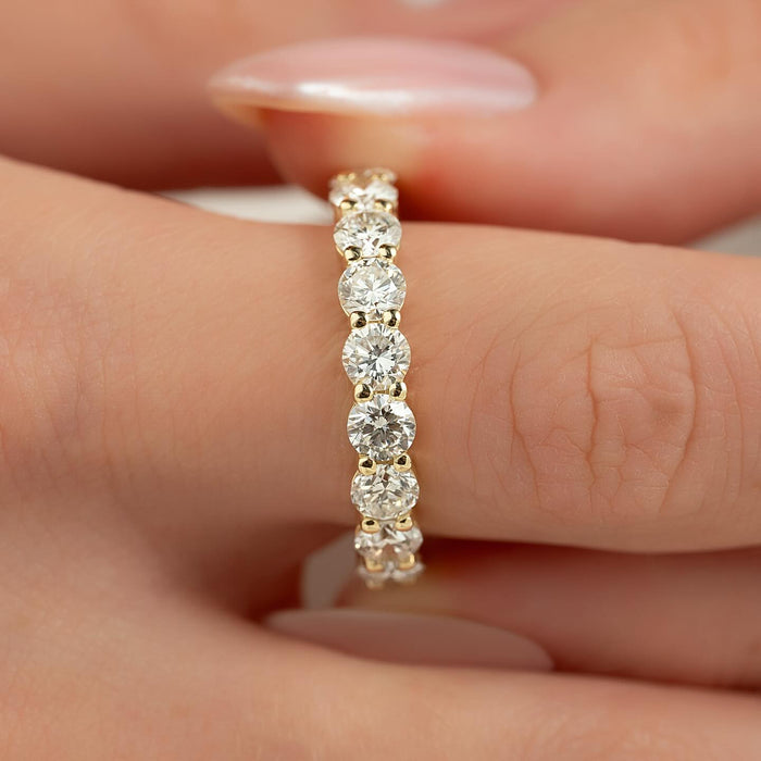 Round moissanite eternity band close up showing shared prong stones in yellow gold