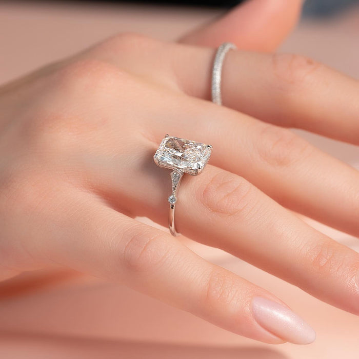 Radiant cut moissanite hidden halo filigree ring worn on hand in white gold