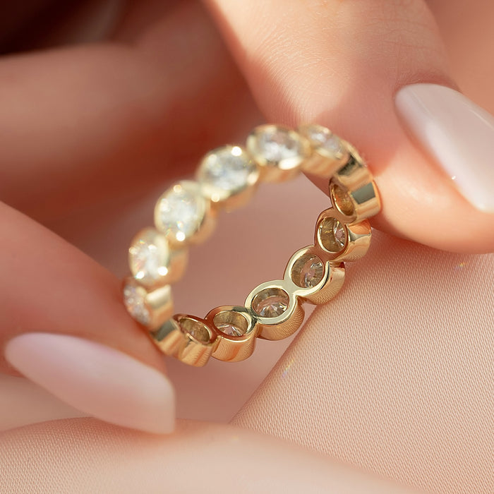 Round moissanite bezel eternity band showing continuous stones in yellow gold