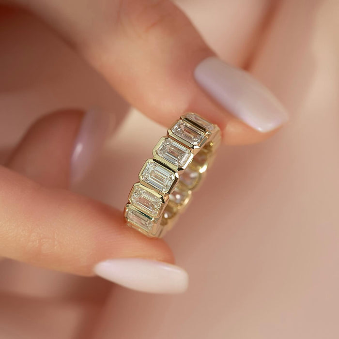 Emerald cut moissanite bezel full eternity band close up in yellow gold