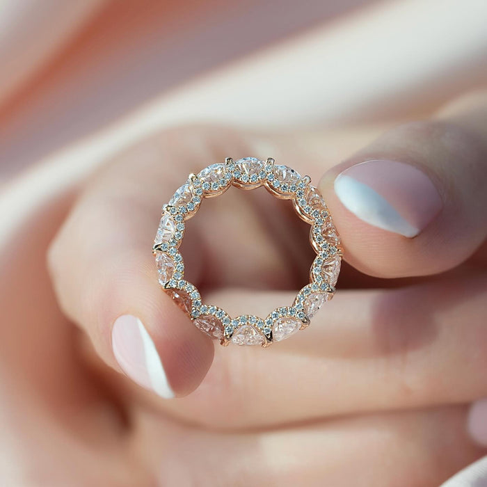 Oval moissanite hidden halo eternity band held up showing full circle in rose gold