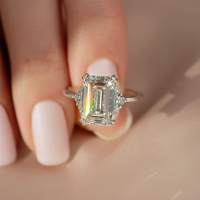 Emerald cut moissanite ring with trio cluster side accents in white gold