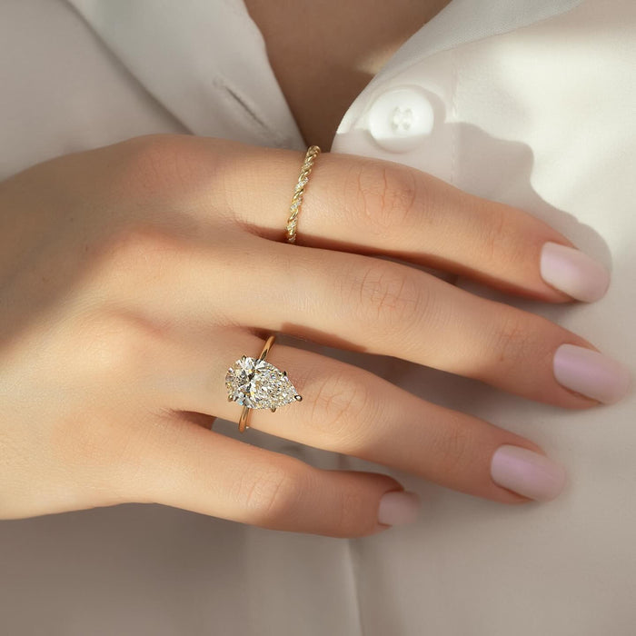 Model wearing pear moissanite hidden halo engagement ring in yellow gold