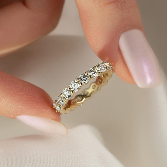 Round moissanite shared prong full eternity band in yellow gold