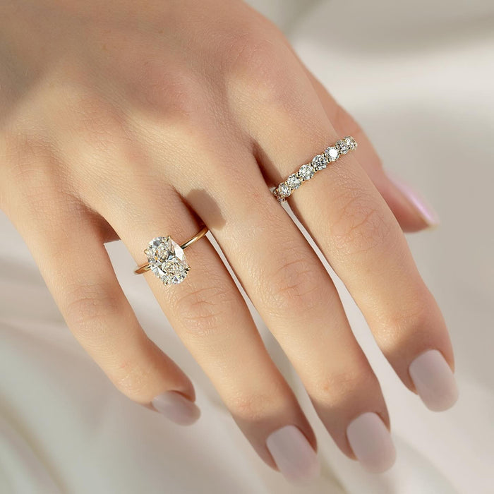 Model wearing round moissanite shared prong eternity band with oval solitaire