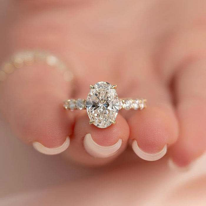 Oval moissanite hidden halo ring with accent band in yellow gold