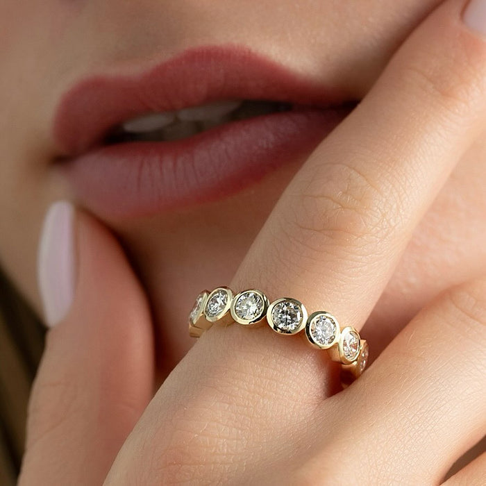 Round Moissanite Bezel Set Eternity Wedding Band in 14K Gold on hand