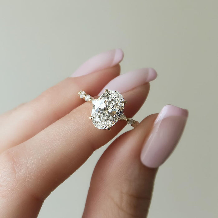 Oval moissanite ring with hidden halo and marquise station accent band in 14K yellow gold