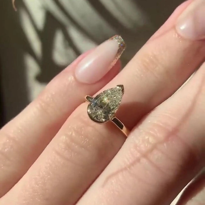 Pear moissanite half bezel ring on hand in rose gold — Mapple Gems