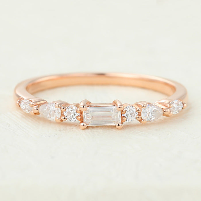 Rose gold multi stone moissanite band with a baguette center flanked by round and pear stones, front view