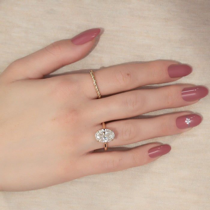 Oval cut moissanite hidden halo knife edge solitaire ring in 14K yellow gold on hand