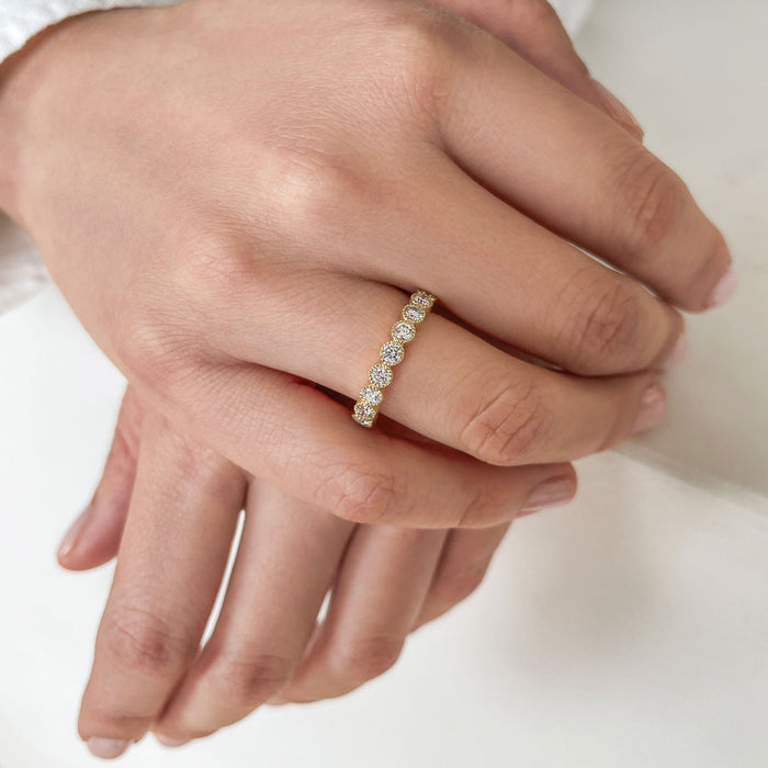 Yellow gold milgrain bezel moissanite band worn on a hand with hands together