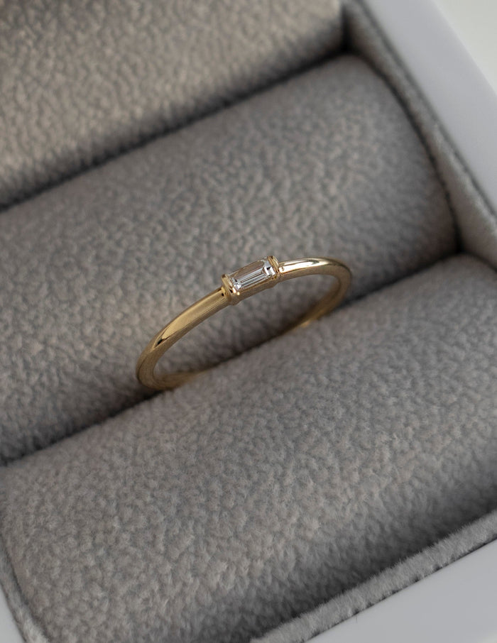 Slim gold stacking ring with one baguette cut moissanite in a ring box
