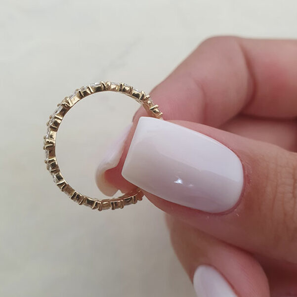 Marquise and round moissanite eternity band held in fingers
