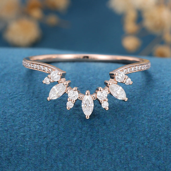 Front view of a curved cluster wedding band with marquise and round moissanite stones and pave shoulders in rose gold