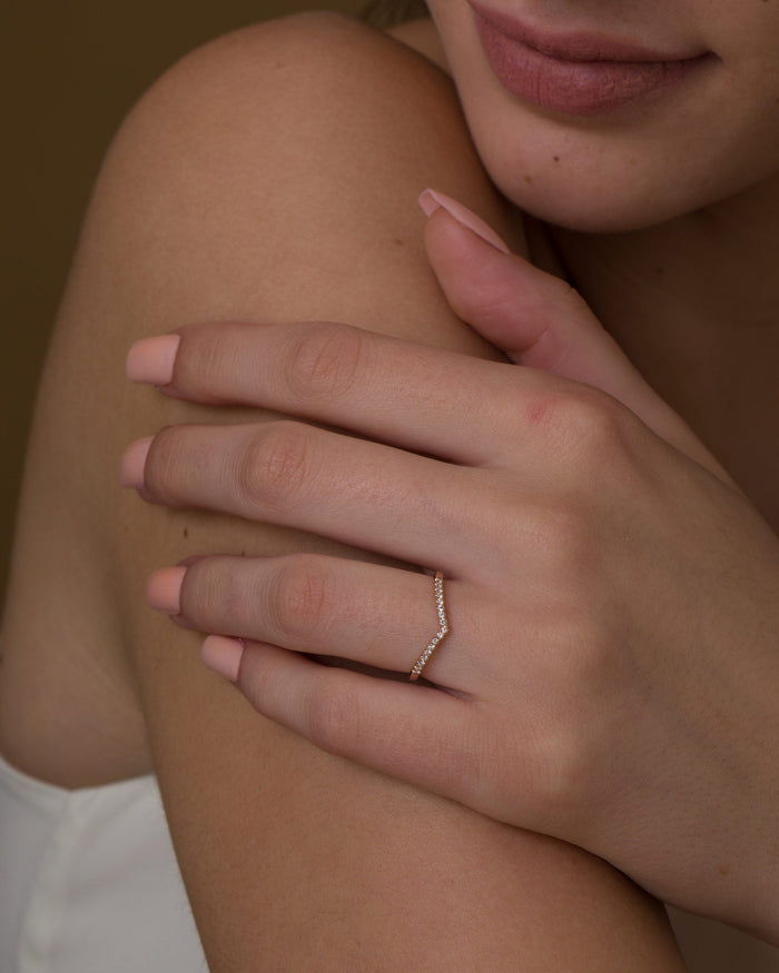Dainty V shaped pave moissanite wedding band in rose gold worn on the ring finger