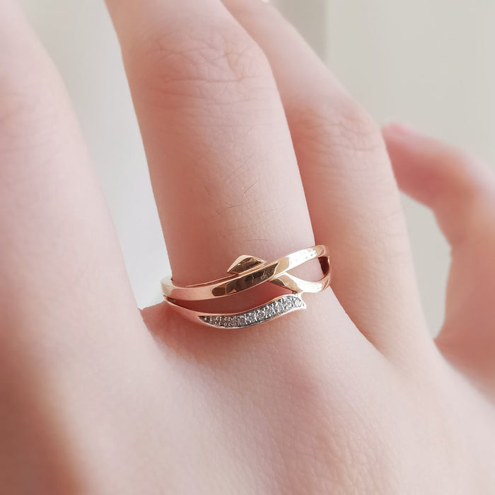 Criss cross moissanite wedding band in rose gold worn on a finger