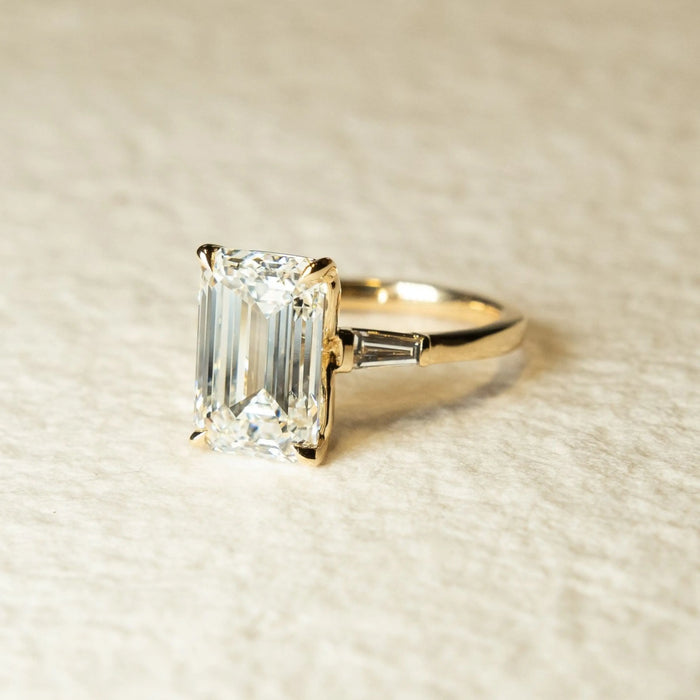 Emerald cut moissanite ring with tapered baguette side stones, angled view