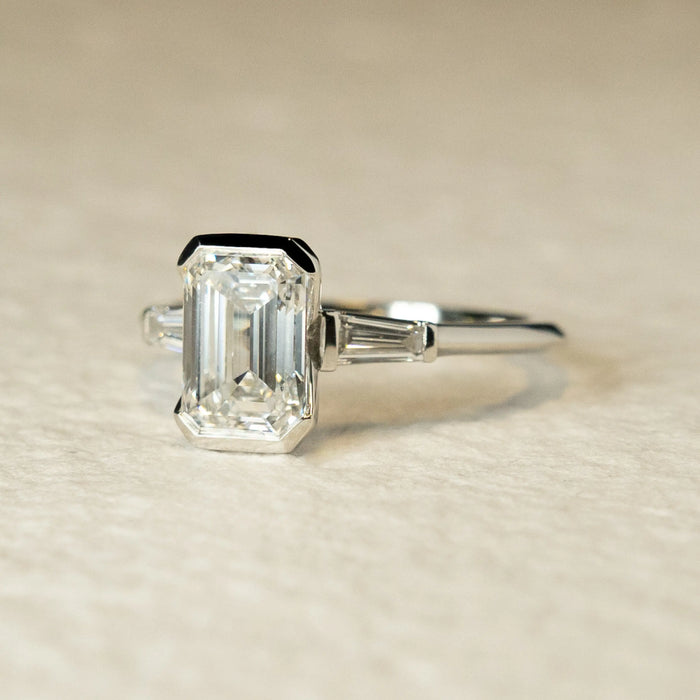 Emerald cut moissanite ring with baguette side stones, angled view