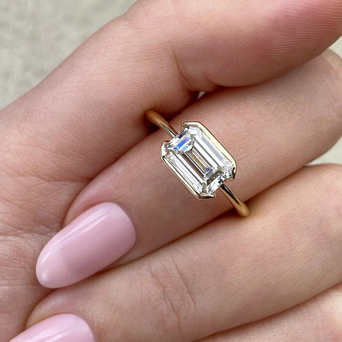 Modern minimalist emerald moissanite engagement ring, angled view