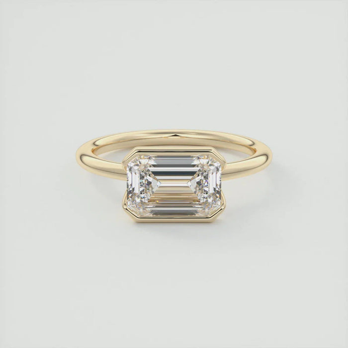 Emerald cut moissanite east west half bezel solitaire ring in 14K gold