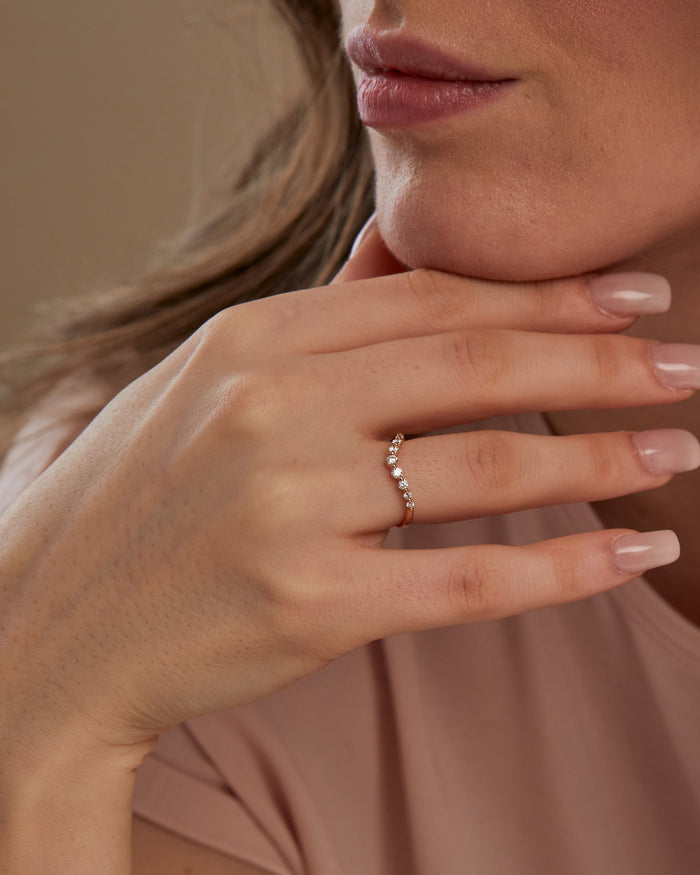 Round moissanite curved band in rose gold worn on the ring finger