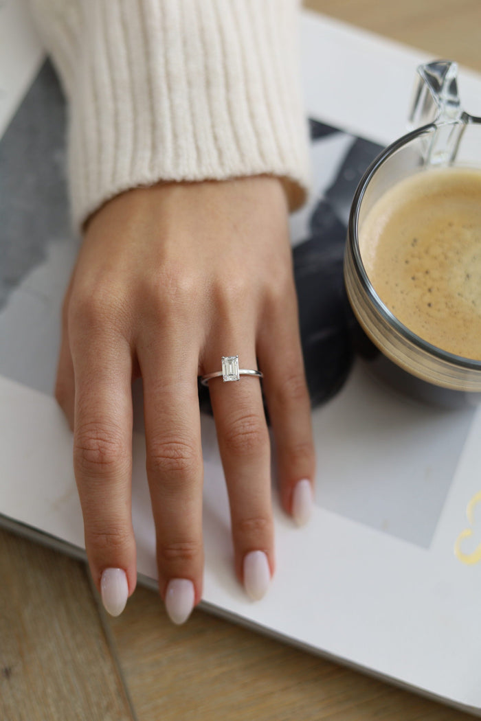 Emerald cut hidden halo engagement ring worn on the hand
