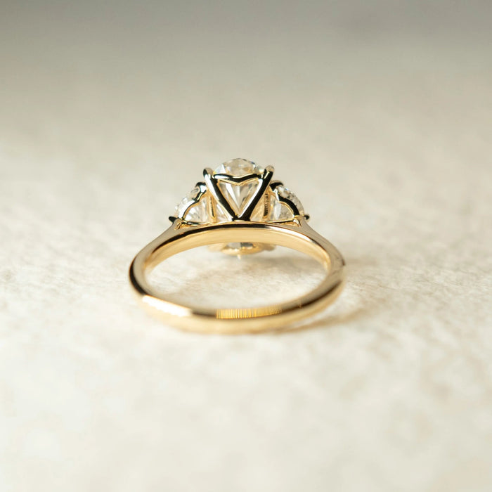 Oval moissanite trilogy ring with diamond accents, angled view