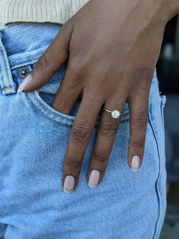 Round hidden halo engagement ring worn on the hand