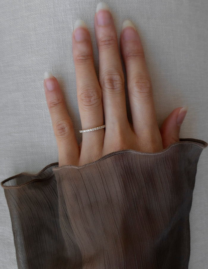 Slim pave half eternity wedding band with round moissanite worn on the ring finger
