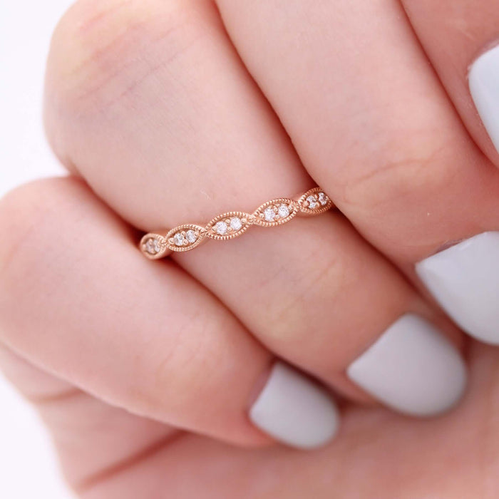 Round moissanite milgrain vintage wedding band in rose gold worn on a finger