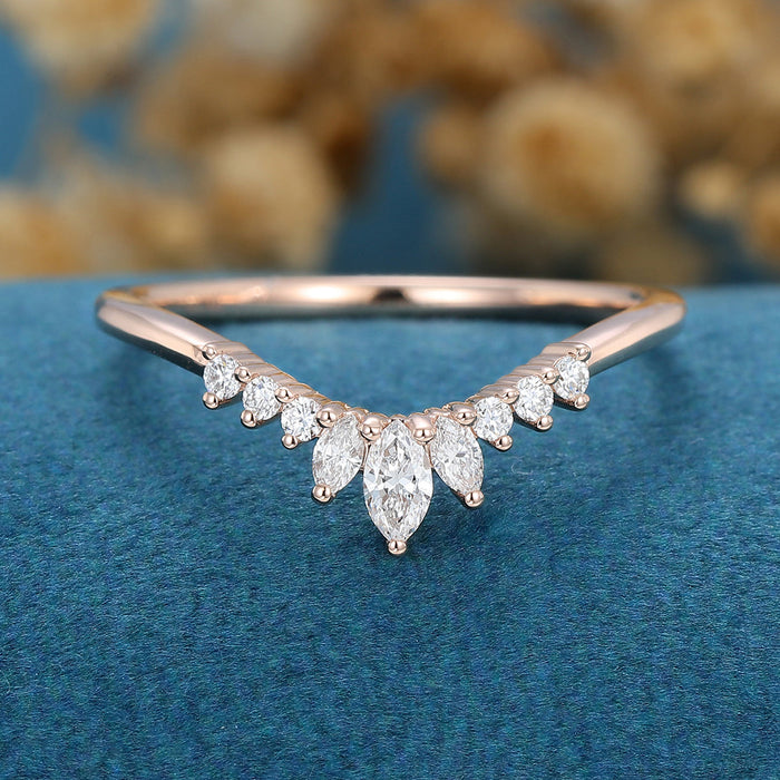 Front view of a curved crown wedding band with three marquise and six round moissanite stones in rose gold