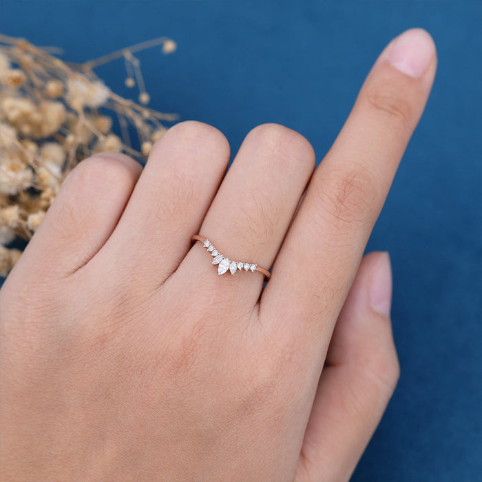 Round and marquise moissanite curved crown wedding band in rose gold worn on a finger
