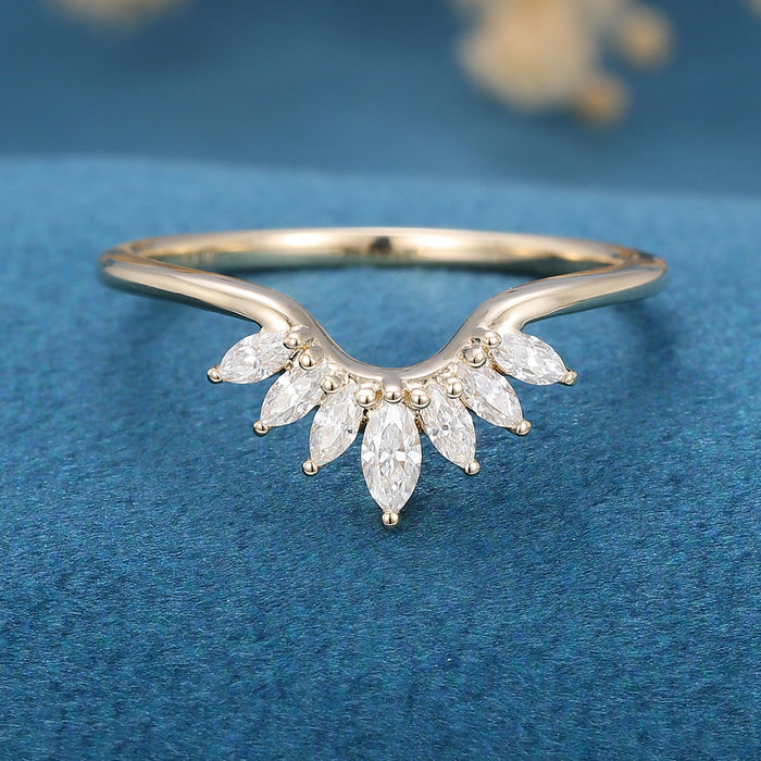 Front view of a curved wedding band with a fan of seven marquise moissanite stones in yellow gold