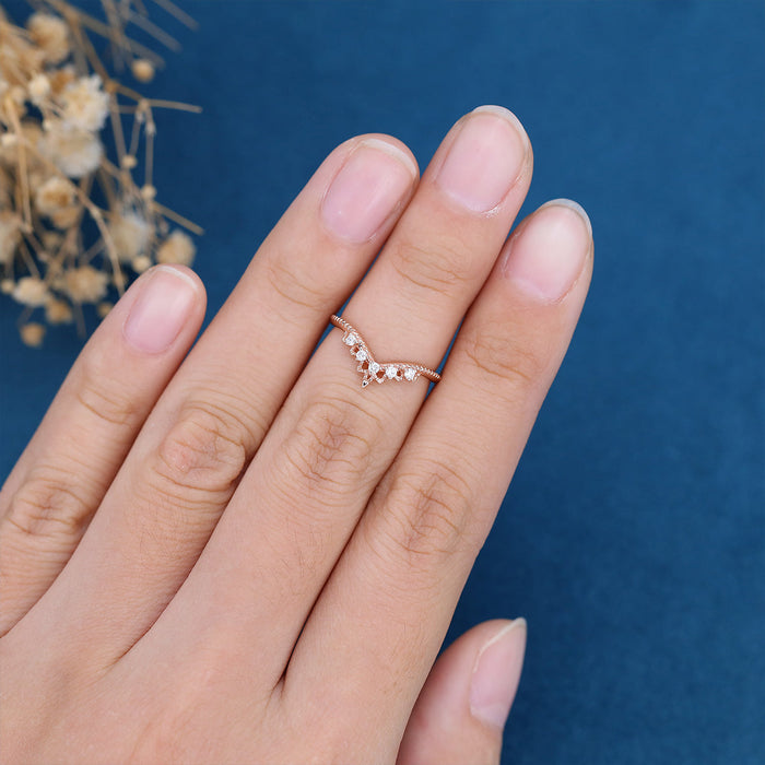 Round moissanite vintage curved V-shaped wedding band in rose gold worn on a finger, engagement ring not included