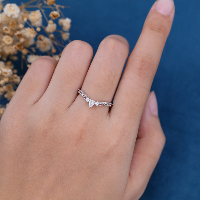 Pear and round moissanite vintage curved milgrain wedding band worn on a finger