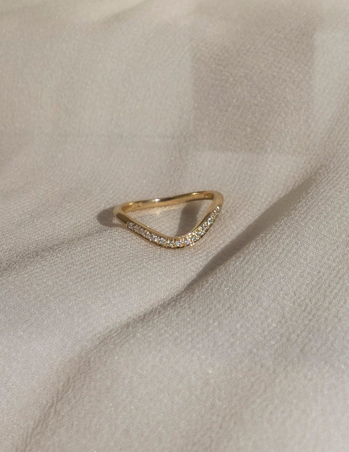 Soft curve pave wedding band with round moissanite resting on fabric