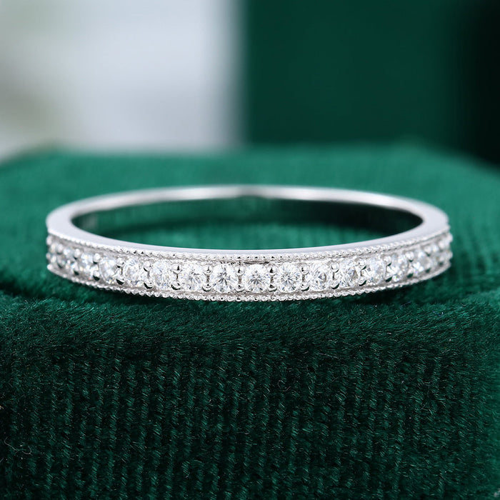 Front view of a vintage band with a row of round moissanite stones and milgrain edges on green velvet