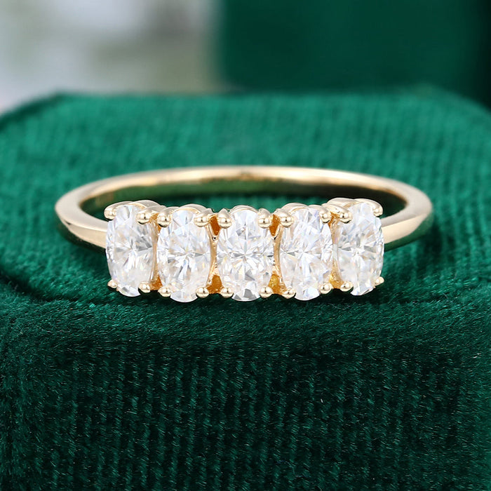 Front view of an oval moissanite five stone wedding band in yellow gold