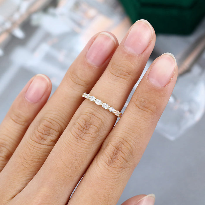 Oval moissanite east west full eternity wedding band in yellow gold worn on the finger