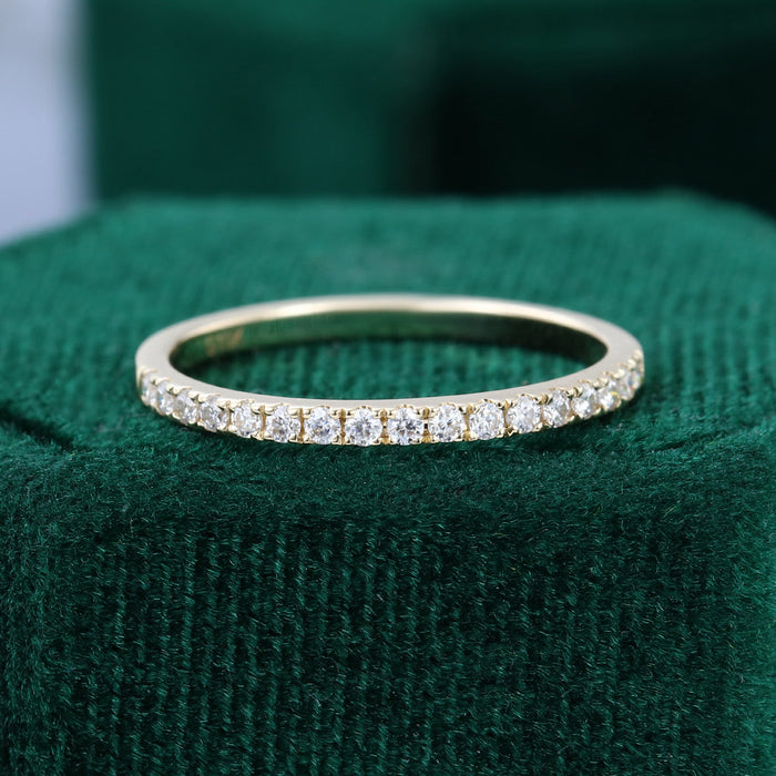 Front view of a thin yellow gold wedding band with a row of pave set round moissanite stones