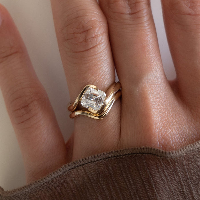 Asscher moissanite swirl bridal set with plain contour band in yellow gold worn on the hand