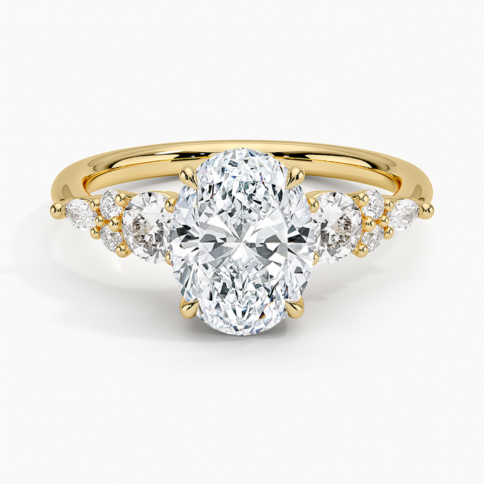 Oval cut lab grown diamond ring with graduated round diamond clusters in yellow gold, top view