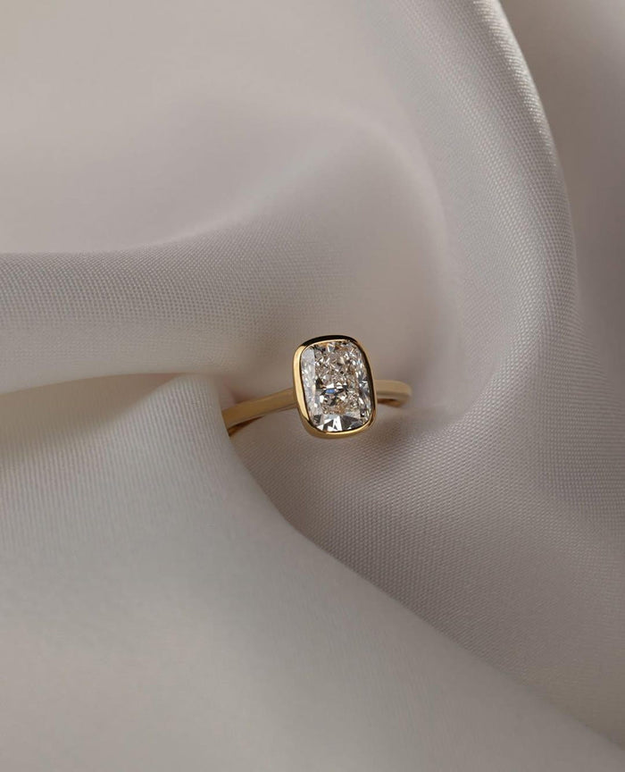 Elongated cushion cut lab grown diamond bezel set solitaire engagement ring in yellow gold