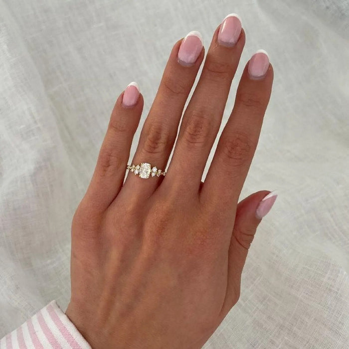 Scattered accent diamonds along the shoulders of the cushion cut ring