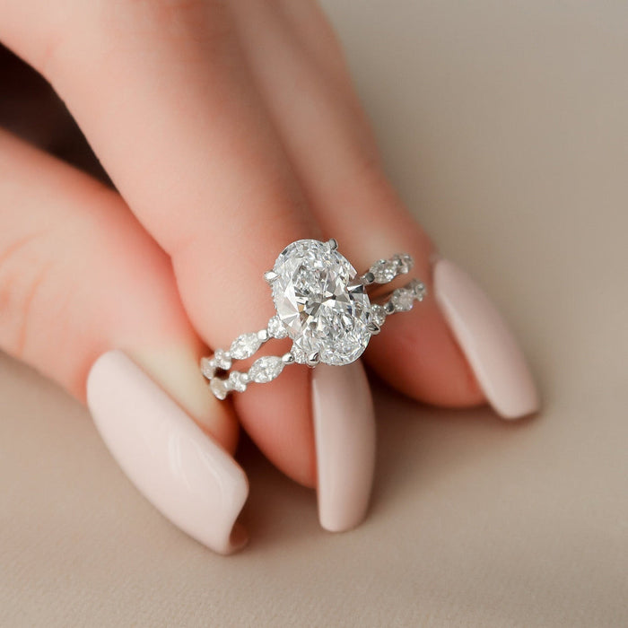 Oval lab grown diamond engagement ring and matching marquise band worn on hand