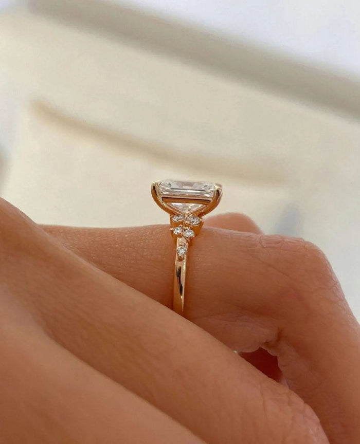 Asymmetric cluster of graduated accent diamonds beside the radiant centre stone