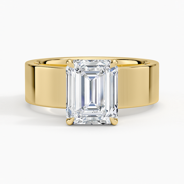 Emerald cut lab grown diamond ring set into a wide flat yellow gold cigar band, top view